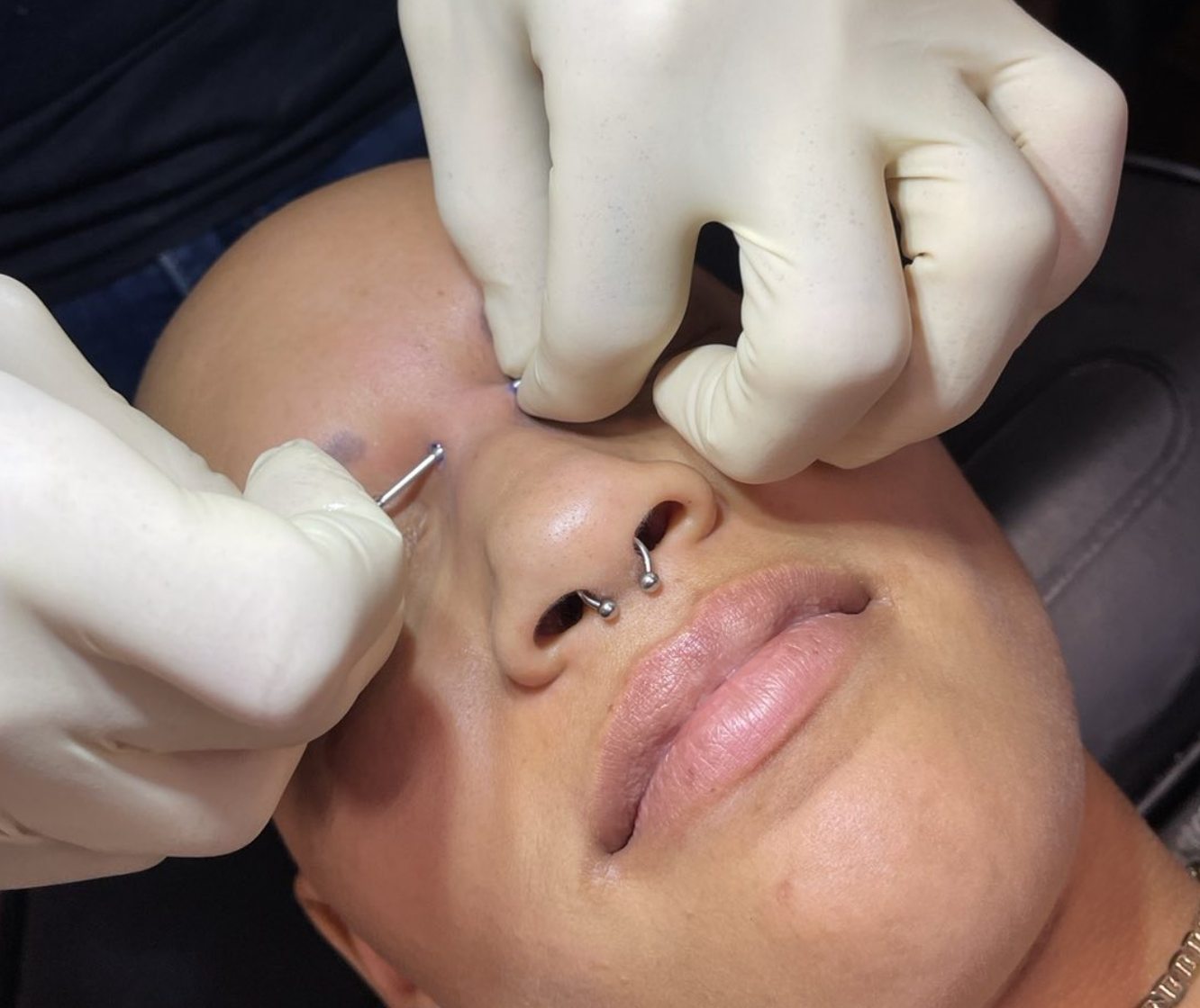 Certified piercer performing a nose piercing